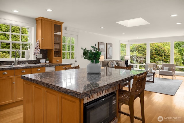3204 Evergreen Point Rd, Medina, WA 98039 - kitchen featuring black microwave, a skylight, light wood-style floors, open floor plan, and dark countertops