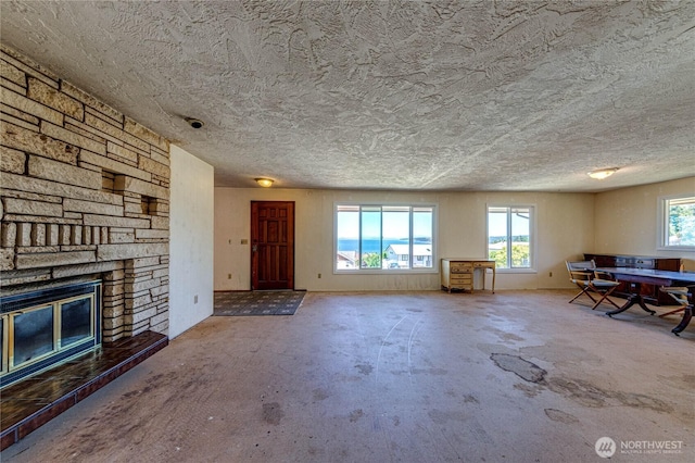 161 Lupine Dr, Sequim, WA 98382 - unfurnished living room featuring concrete floors, a stone fireplace, and a textured ceiling