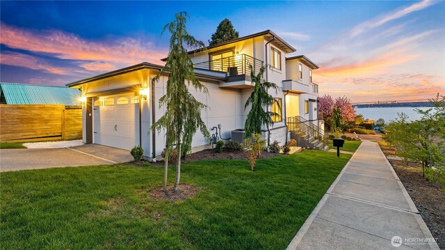 1006 4th St W, Kirkland, WA 98033 - modern home with a balcony, concrete driveway, stucco siding, an attached garage, and a water view