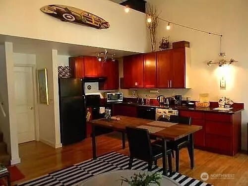 1750 NW 58th St, Seattle, WA 09107 - kitchen with freestanding refrigerator, stainless steel microwave, dark brown cabinets, dark countertops, and light wood-style flooring