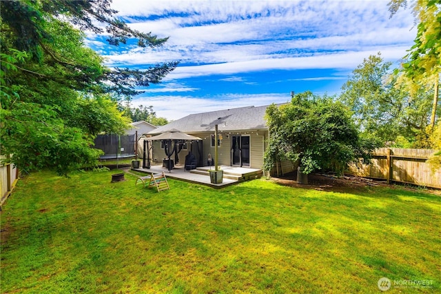 1390 Jordan Ct, Oak Harbor, WA 98277 - rear view of property featuring a trampoline, a gazebo, a fenced backyard, and a wooden deck