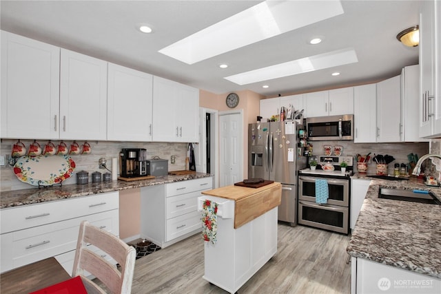 118 Ocean Lake Way NE, Ocean Shores, WA 98569 - kitchen featuring appliances with stainless steel finishes, a skylight, light stone counters, decorative backsplash, and recessed lighting