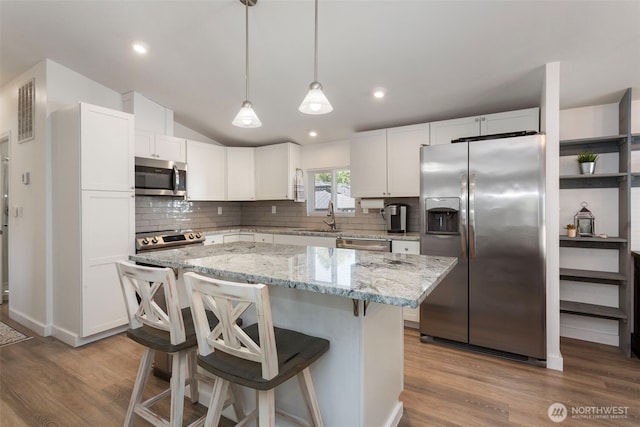 207 6th St, Sultan, WA 98294 - kitchen with appliances with stainless steel finishes, tasteful backsplash, wood finished floors, vaulted ceiling, and recessed lighting