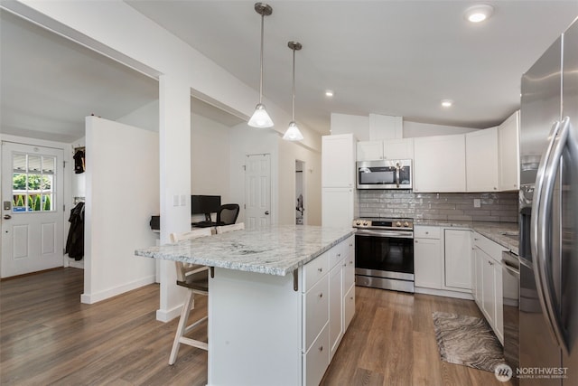 207 6th St, Sultan, WA 98294 - kitchen with appliances with stainless steel finishes, lofted ceiling, tasteful backsplash, a center island, and wood finished floors
