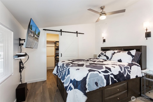 207 6th St, Sultan, WA 98294 - bedroom with a barn door, wood finished floors, a walk in closet, vaulted ceiling, and a closet