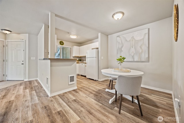 11130 SE 208th St Unit N101, Kent, WA 98031 - kitchen with freestanding refrigerator, white cabinets, a peninsula, and light wood-style floors