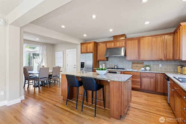 2648 116th Ave NE, Bellevue, WA 98004 - kitchen with stainless steel appliances, under cabinet range hood, a kitchen island, backsplash, and light wood-style flooring
