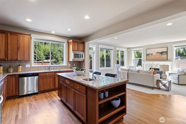 2648 116th Ave NE, Bellevue, WA 98004 - kitchen featuring appliances with stainless steel finishes, brown cabinets, an island with sink, tasteful backsplash, and recessed lighting