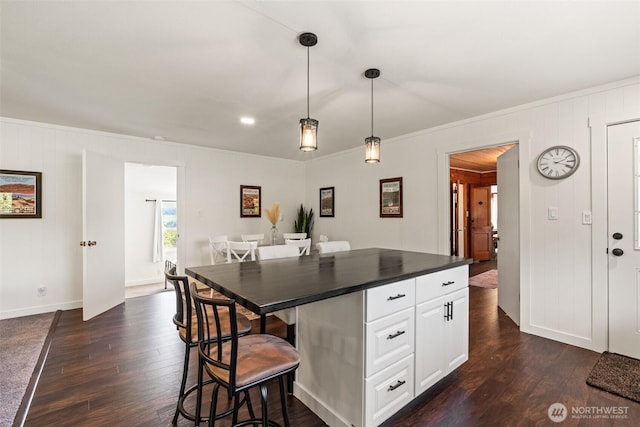 9753 Nibbelink Rd, Peshastin, WA 98847 - kitchen with dark countertops, ornamental molding, dark wood-style floors, white cabinetry, and a breakfast bar