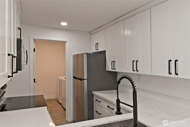11811 93rd Ln NE Unit 102, Kirkland, WA 98034 - kitchen featuring separate washer and dryer, white cabinets, light wood finished floors, recessed lighting, and freestanding refrigerator