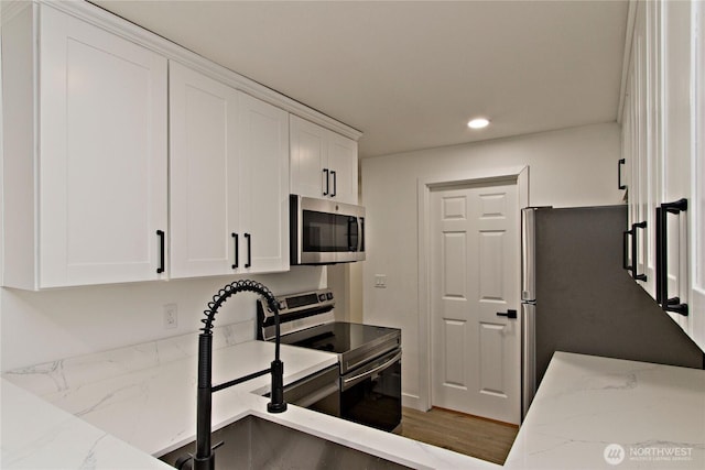 11811 93rd Ln NE Unit 102, Kirkland, WA 98034 - kitchen with stainless steel appliances, recessed lighting, white cabinets, and light stone counters