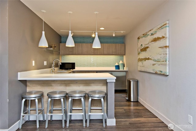 11811 93rd Ln NE Unit 102, Kirkland, WA 98034 - kitchen with tasteful backsplash, a breakfast bar, light countertops, and dark wood-style flooring