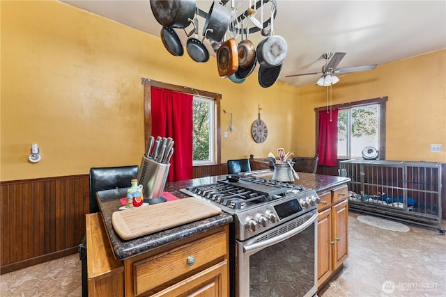 701 13th St SE, Puyallup, WA 98372 - kitchen with stainless steel gas range, ceiling fan, a wainscoted wall, brown cabinets, and wood walls