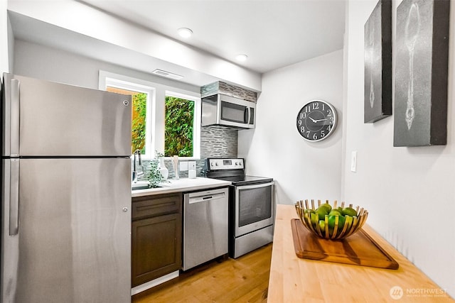 3406 SW Manning St, Seattle, WA 98126 - kitchen featuring stainless steel appliances, light wood finished floors, tasteful backsplash, and light countertops