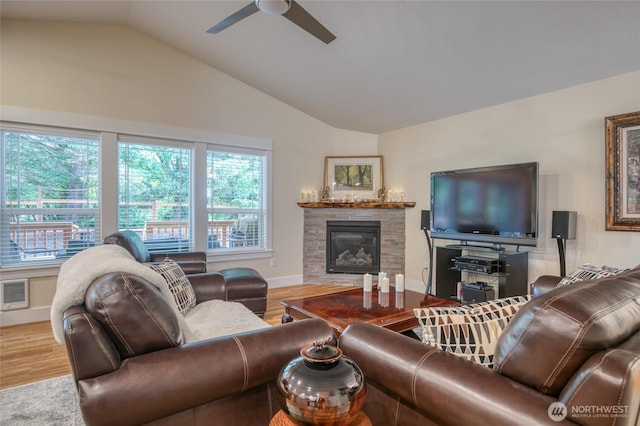 789 Island Cir SE, Ocean Shores, WA 98569 - living area featuring vaulted ceiling, a stone fireplace, a ceiling fan, and wood finished floors