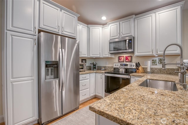 789 Island Cir SE, Ocean Shores, WA 98569 - kitchen featuring stainless steel appliances, white cabinets, light stone countertops, recessed lighting, and light wood finished floors
