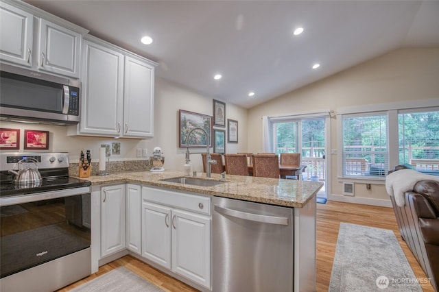 789 Island Cir SE, Ocean Shores, WA 98569 - kitchen with appliances with stainless steel finishes, a peninsula, white cabinetry, light wood-style floors, and vaulted ceiling