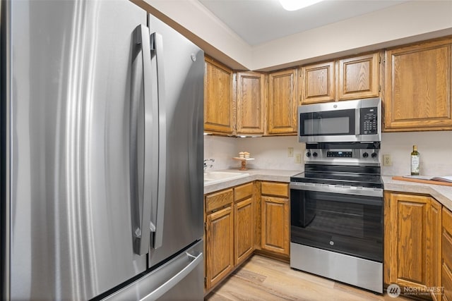 300 N Sequim Ave Unit 15, Sequim, WA 98382 - kitchen with stainless steel appliances, light countertops, brown cabinetry, and light wood-style floors