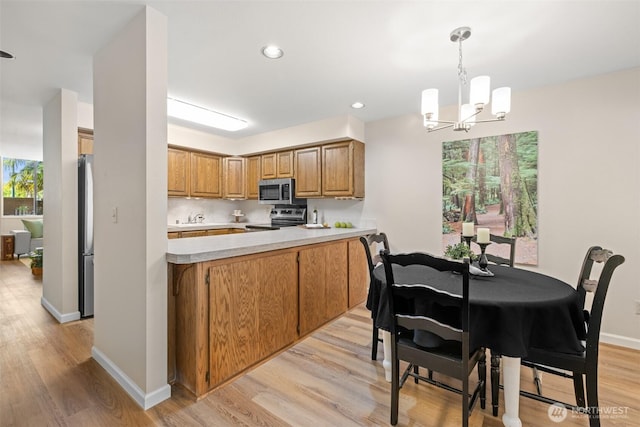 300 N Sequim Ave Unit 15, Sequim, WA 98382 - kitchen featuring appliances with stainless steel finishes, light wood-type flooring, a chandelier, light countertops, and brown cabinets