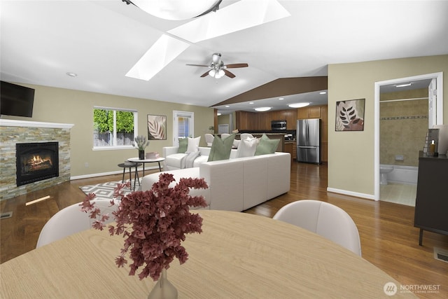 22526 87th Pl W, Edmonds, WA 98026 - dining area with a skylight, dark wood finished floors, a stone fireplace, vaulted ceiling, and a ceiling fan