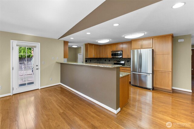 22526 87th Pl W, Edmonds, WA 98026 - kitchen with stainless steel appliances, light wood finished floors, a peninsula, light stone countertops, and decorative backsplash
