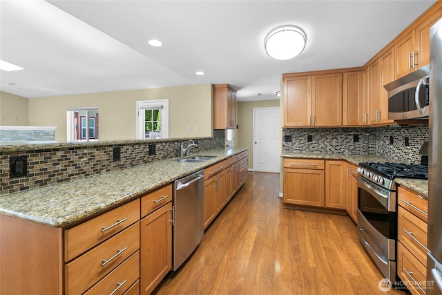 22526 87th Pl W, Edmonds, WA 98026 - kitchen featuring stainless steel appliances, backsplash, light wood-type flooring, light stone countertops, and a peninsula