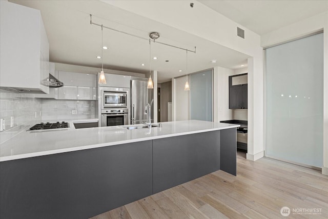 737 Olive Way Unit 1903, Seattle, WA 98101 - kitchen with appliances with stainless steel finishes, modern cabinets, a peninsula, light wood-style flooring, and light countertops