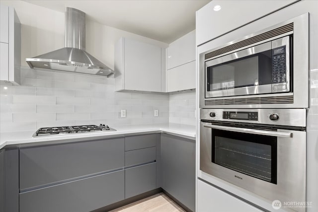 737 Olive Way Unit 1903, Seattle, WA 98101 - kitchen featuring wall chimney exhaust hood, gray cabinetry, stainless steel appliances, modern cabinets, and tasteful backsplash