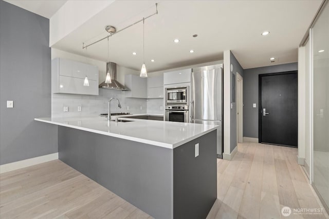 737 Olive Way Unit 1903, Seattle, WA 98101 - kitchen featuring wall chimney exhaust hood, stainless steel appliances, modern cabinets, a peninsula, and backsplash
