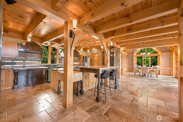 991 Lakeview St, Bellingham, WA 98229 - kitchen with stone tile floors, backsplash, a wooden ceiling with exposed beams, a breakfast bar, and stainless steel fridge
