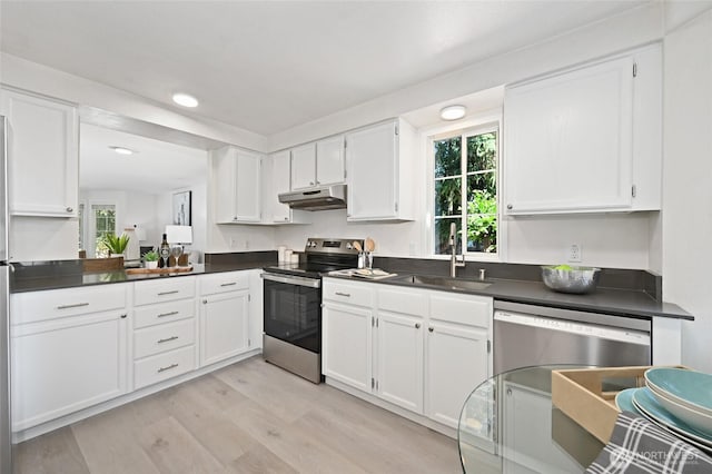 10263 NE 129th Ln, Kirkland, WA 98034 - kitchen with appliances with stainless steel finishes, under cabinet range hood, dark countertops, light wood-style floors, and white cabinetry