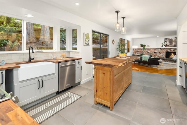 6687 NE Bayview Blvd, Bainbridge Island, WA 98110 - kitchen featuring wooden counters, stainless steel dishwasher, tasteful backsplash, open floor plan, and pendant lighting