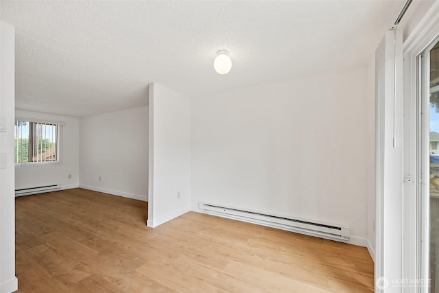 6610 S Madison St, Tacoma, WA 98409 - unfurnished room with a baseboard heating unit, light wood-style floors, and a textured ceiling