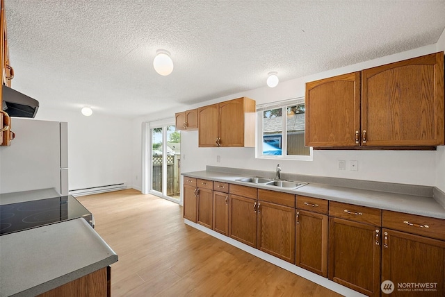 6610 S Madison St, Tacoma, WA 98409 - kitchen featuring a baseboard radiator, freestanding refrigerator, brown cabinets, light wood finished floors, and a textured ceiling