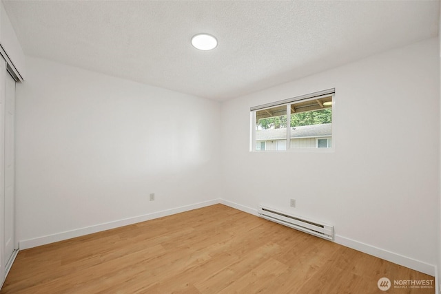 6610 S Madison St, Tacoma, WA 98409 - spare room with a baseboard heating unit, light wood finished floors, and a textured ceiling