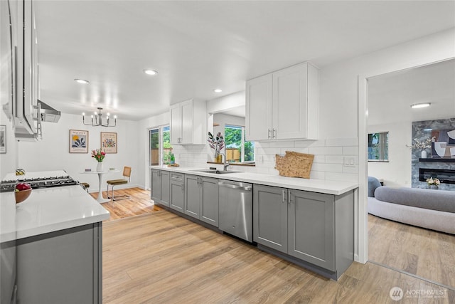 8808 NE 139th St, Kirkland, WA 98034 - kitchen with stainless steel dishwasher, gray cabinetry, decorative backsplash, light wood-style flooring, and a chandelier