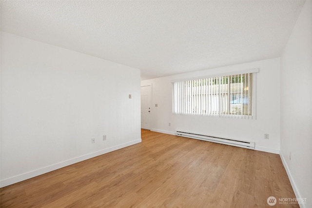6604 S Madison St, Tacoma, WA 98409 - empty room featuring a baseboard heating unit and light wood-style flooring