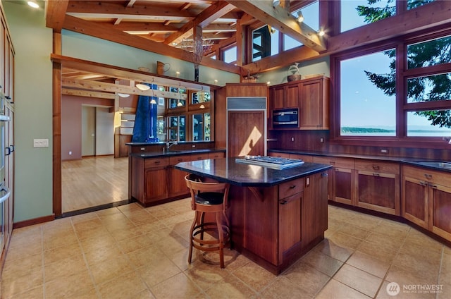 9913 Point View St NE, Olympia, WA 98516 - kitchen with appliances with stainless steel finishes, a center island, beamed ceiling, light tile patterned floors, and brown cabinetry