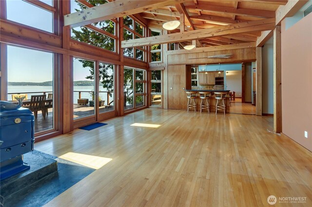 9913 Point View St NE, Olympia, WA 98516 - living room with high vaulted ceiling, wood finished floors, a water view, beamed ceiling, and wooden walls