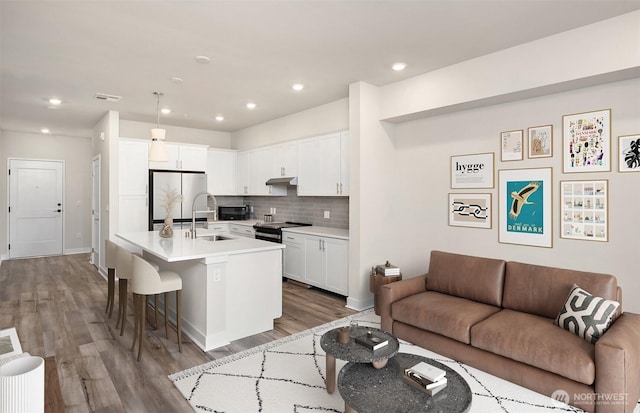 6901 NE 184th Ln Unit 103, Kenmore, WA 98028 - kitchen with stainless steel refrigerator, under cabinet range hood, open floor plan, a breakfast bar, and wood finished floors