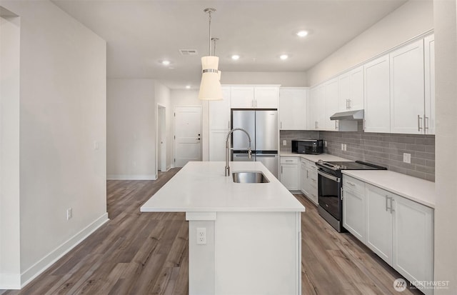 6901 NE 184th Ln Unit 103, Kenmore, WA 98028 - kitchen with range with electric cooktop, black microwave, freestanding refrigerator, under cabinet range hood, and a center island with sink
