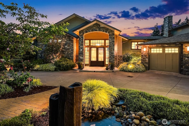 9620 NE 28th St, Clyde Hill, WA 98004 - exterior entry at dusk with stone siding, driveway, french doors, and an attached garage