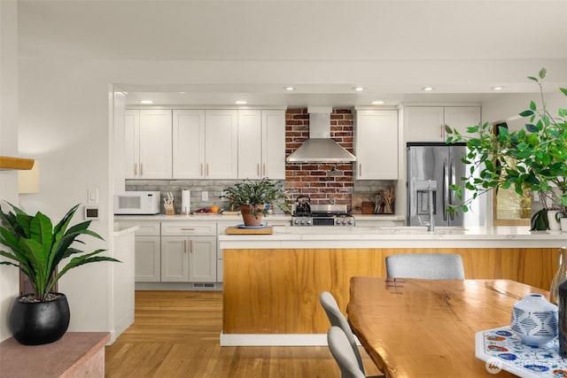 3912 NE 127th St, Seattle, WA 98125 - kitchen featuring wall chimney exhaust hood, stove, white microwave, stainless steel fridge, and decorative backsplash