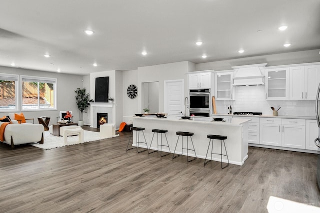 3941 233rd St SE, Bothell, WA 98021 - kitchen featuring custom exhaust hood, a kitchen breakfast bar, open floor plan, wood finished floors, and white cabinets
