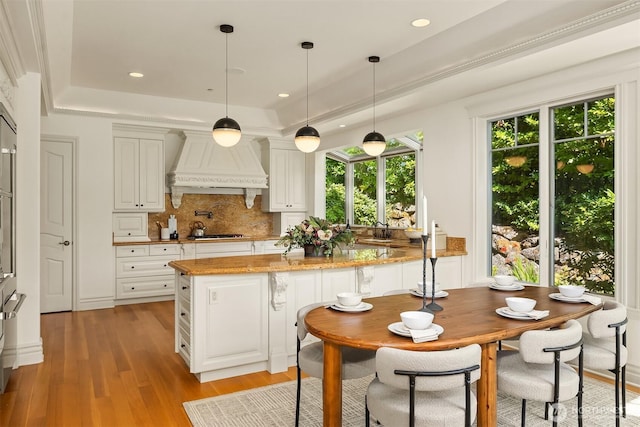 3210 Hunts Point Rd, Hunts Point, WA 98004 - kitchen with custom exhaust hood, a raised ceiling, decorative backsplash, light wood-style floors, and stainless steel gas cooktop