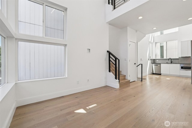 805 Taylor Ave N Unit D, Seattle, WA 98109 - unfurnished living room with light wood-style flooring, a high ceiling, stairway, and recessed lighting