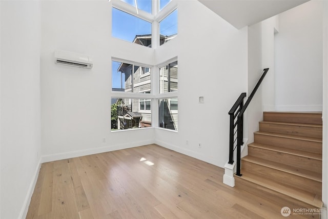805 Taylor Ave N Unit D, Seattle, WA 98109 - spare room featuring a wall unit AC, wood finished floors, stairs, and a high ceiling