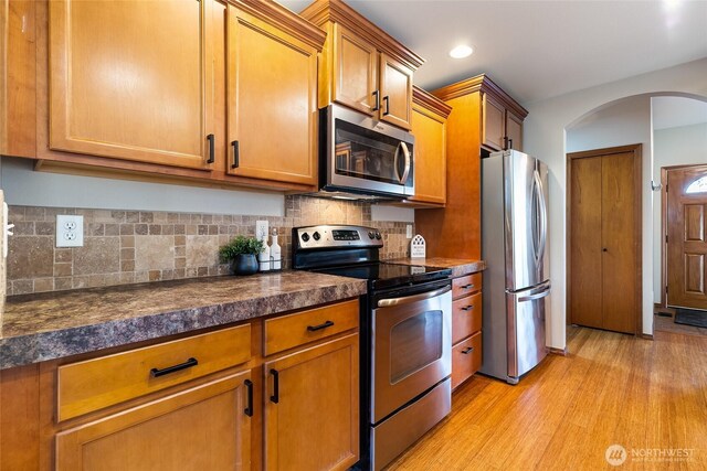 5983 Honeycutt Ct, Ferndale, WA 98248 - kitchen with stainless steel appliances, dark countertops, arched walkways, brown cabinetry, and recessed lighting
