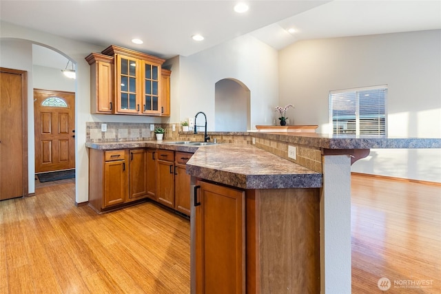 5983 Honeycutt Ct, Ferndale, WA 98248 - kitchen with a peninsula, light wood finished floors, arched walkways, brown cabinets, and a breakfast bar area