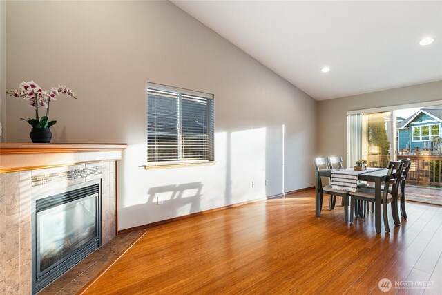 5983 Honeycutt Ct, Ferndale, WA 98248 - dining space with wood finished floors, high vaulted ceiling, a tiled fireplace, and recessed lighting